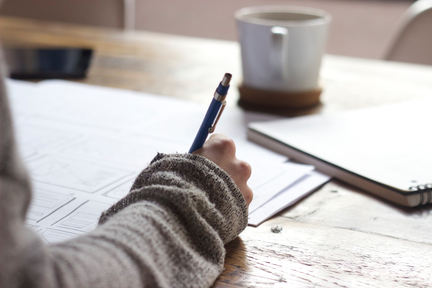 Hand writing in a notebook on a wooden table