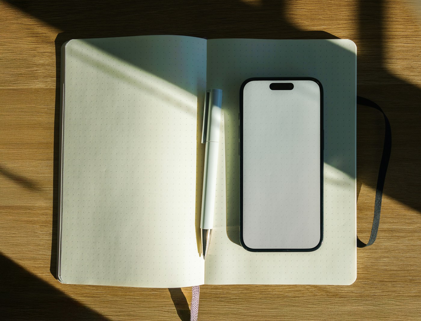 Open notebook with a pen beside a smartphone on a wooden table