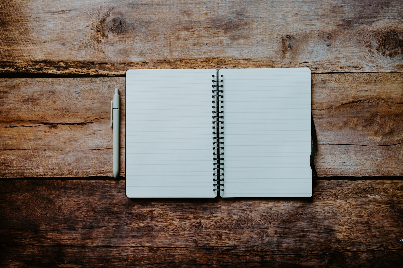 Open spiral notebook with a pen on a wooden table
