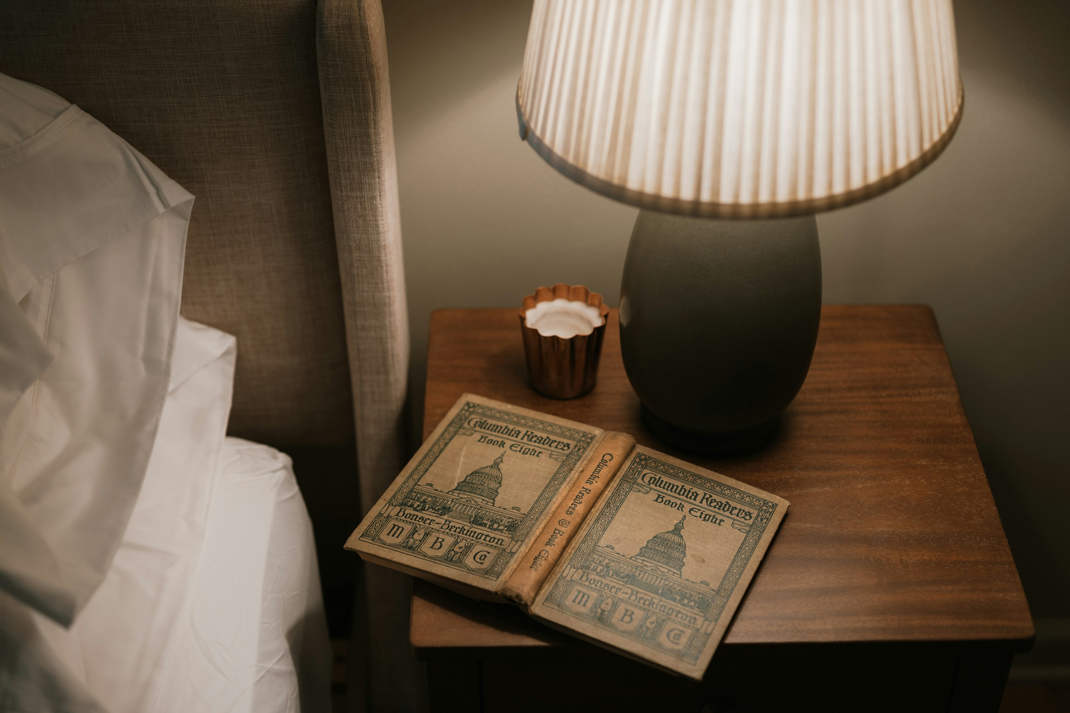Open book on a bedside table with a warm lamp