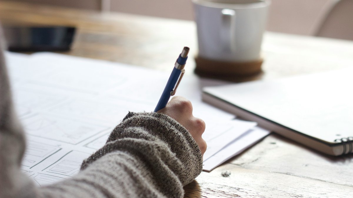Hand writing in a notebook on a wooden table