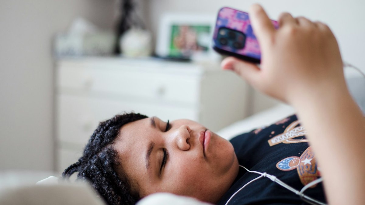 Person lying in bed looking at a phone