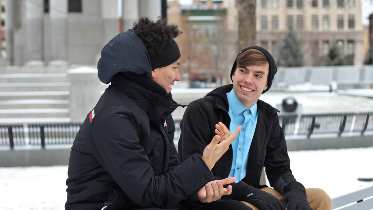 Two friends talking while sitting on a park bench