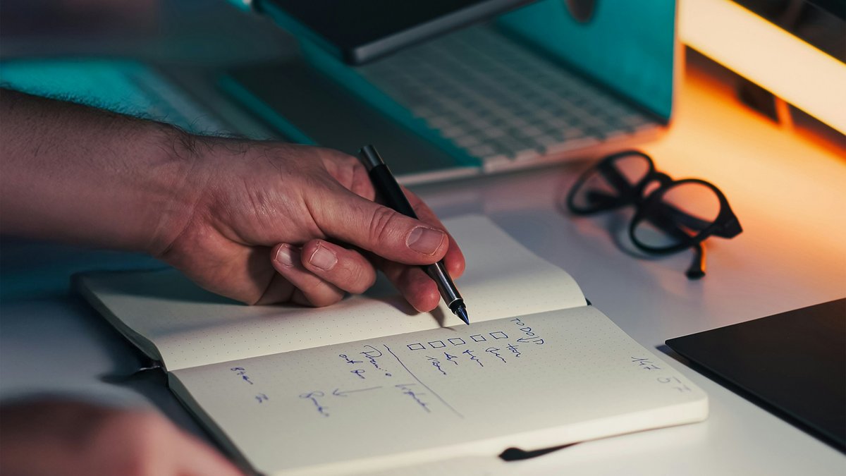 Hand writing in a notebook on a desk