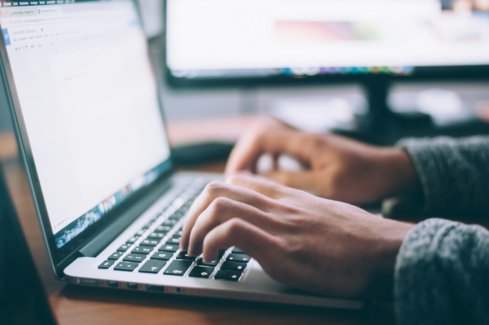 Hands typing on a laptop at a desk