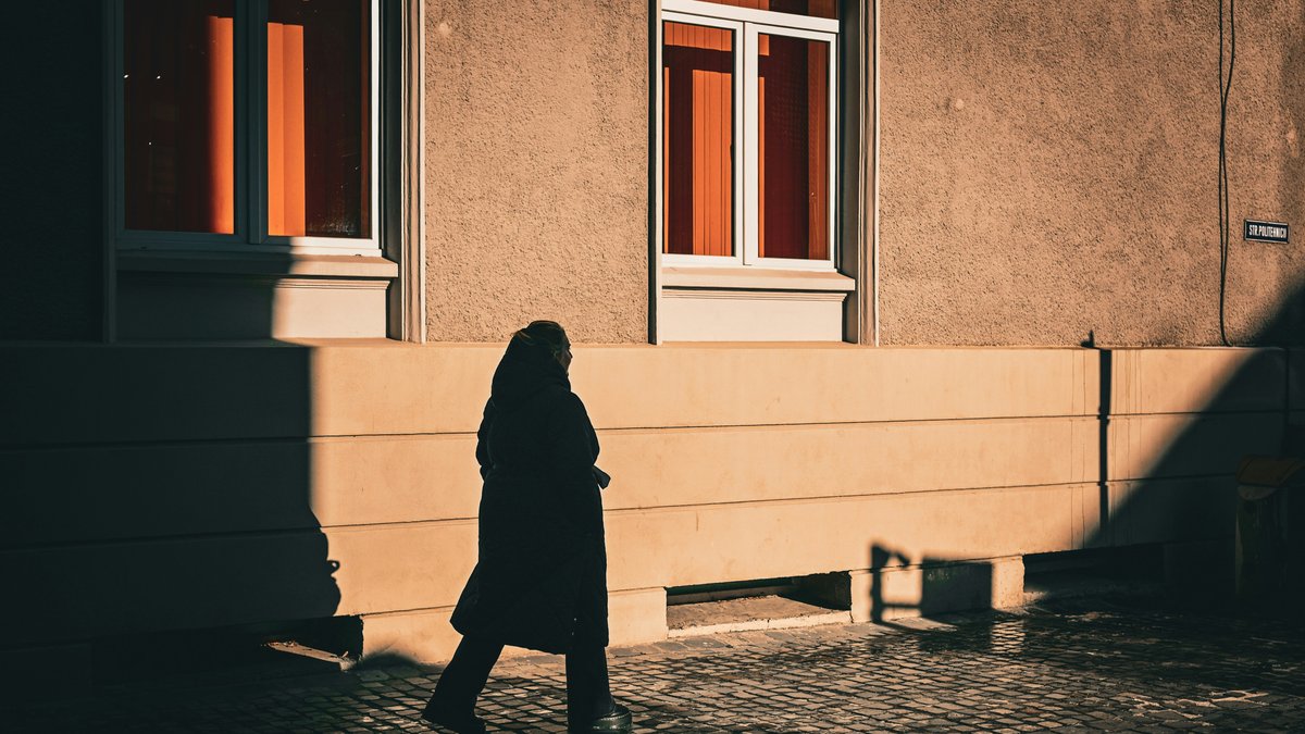 Silhouette of a person walking alone on a sunlit cobblestone street