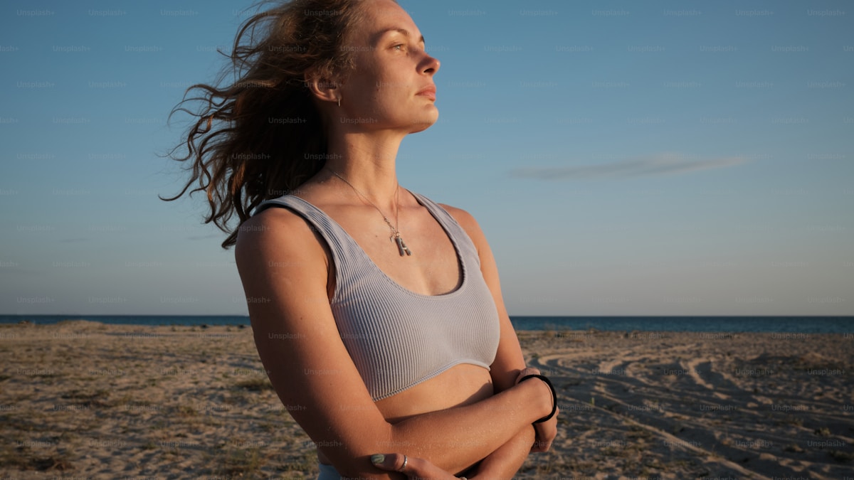 A woman standing on a beach with her arms crossed
