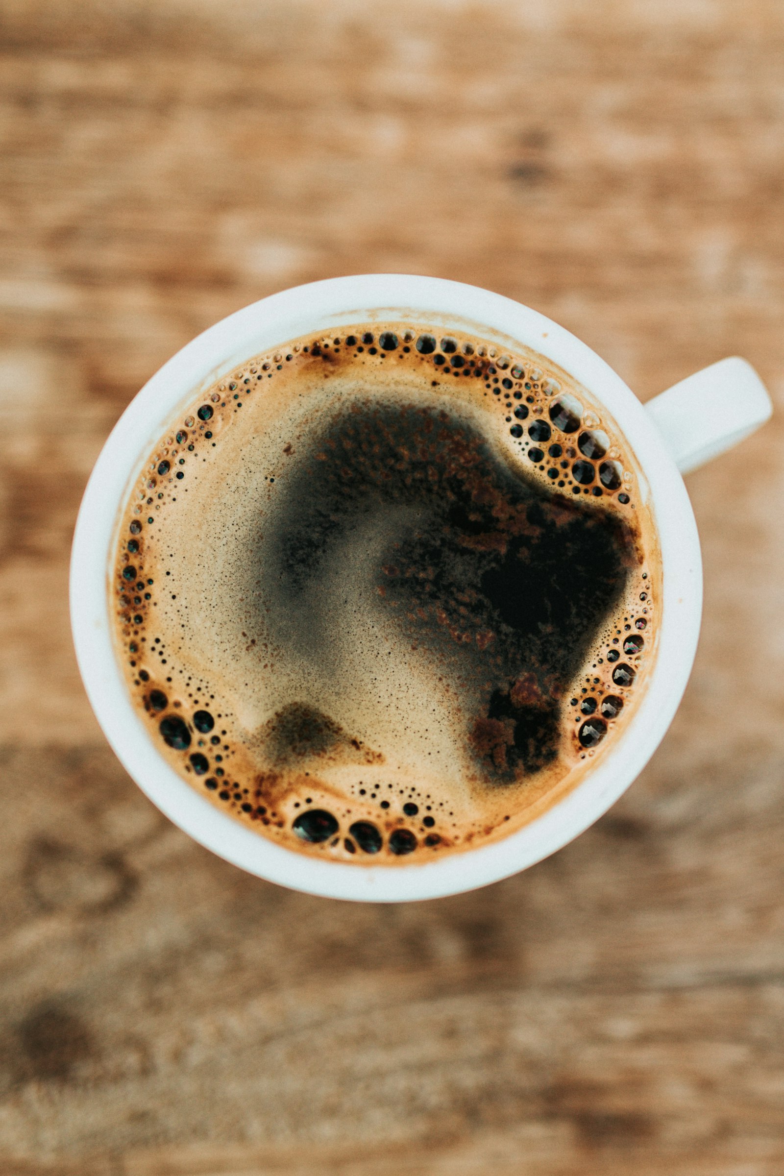 A single white mug of coffee on a wooden table