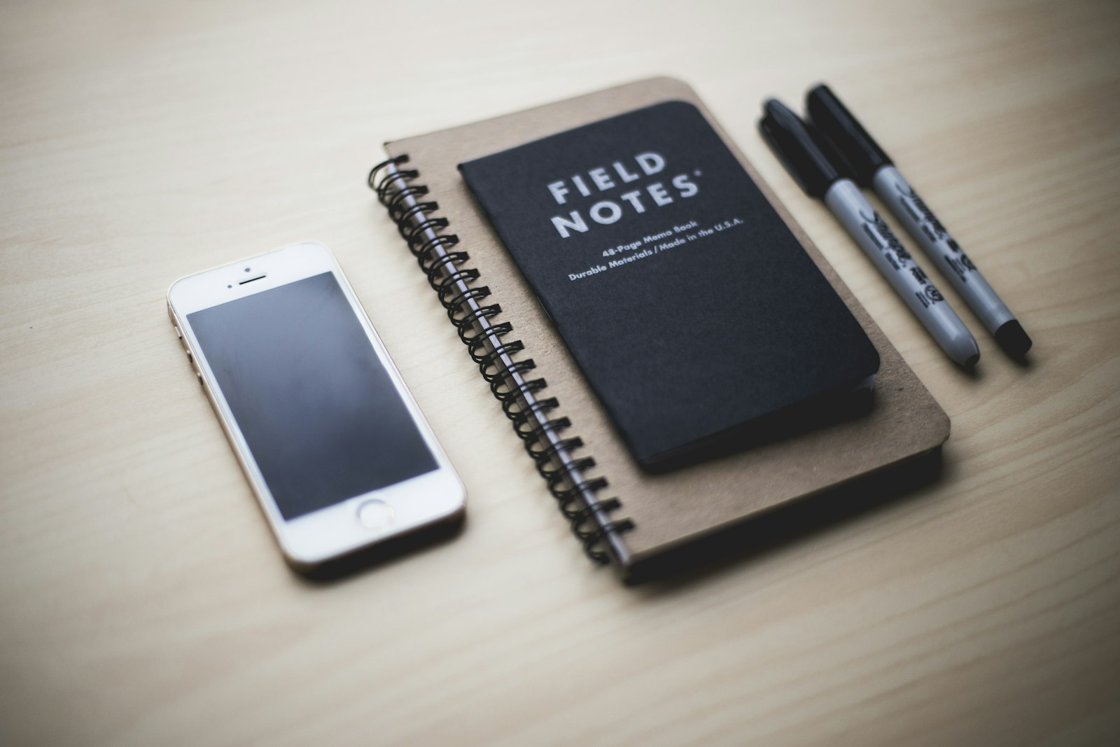 A phone resting near a small notebook, ready for jotting down ideas